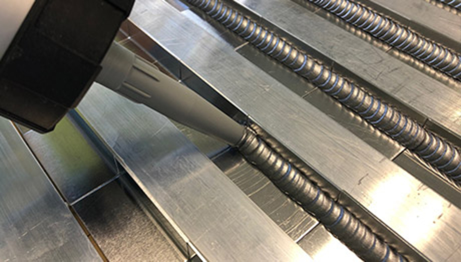 Jetzt zum Klebtechnik-Seminar anmelden. Aluminium-Profil wird mit silberfarbenem Klebstoff mittels einer Dosierpumpe versehen.